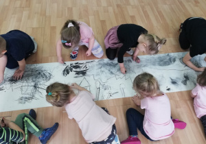 Dzieci zapełniają karton własnymi rysunkami, trzymając się wyznaczonej przestrzeni.